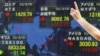 A man gestures in front of a securities firm's electronic stock board in Tokyo, Aug. 16, 2012. 