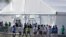 FILE - Detained migrant children from Central America line up to enter a tent at the Homestead Temporary Shelter for Unaccompanied Children in Homestead, Florida, Feb. 19, 2019. 