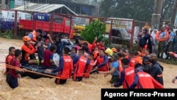 This handout photo taken on Dec. 16, 2021 and received from the Philippine Coast Guard shows rescue workers evacuating residents from their flooded homes in Cagayan de Oro City, on the island of Mindanao. (Photo by Handout / Philippine Coast Guard) 
