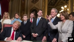 川普总统在众议院议长瑞安(前排右起第三人)和众议院少数党领袖佩洛西(前排右起第一人)等国会领袖和家人的陪同下在国会大厦将内阁人员的任命正式签署成为法律(2017年1月20日)