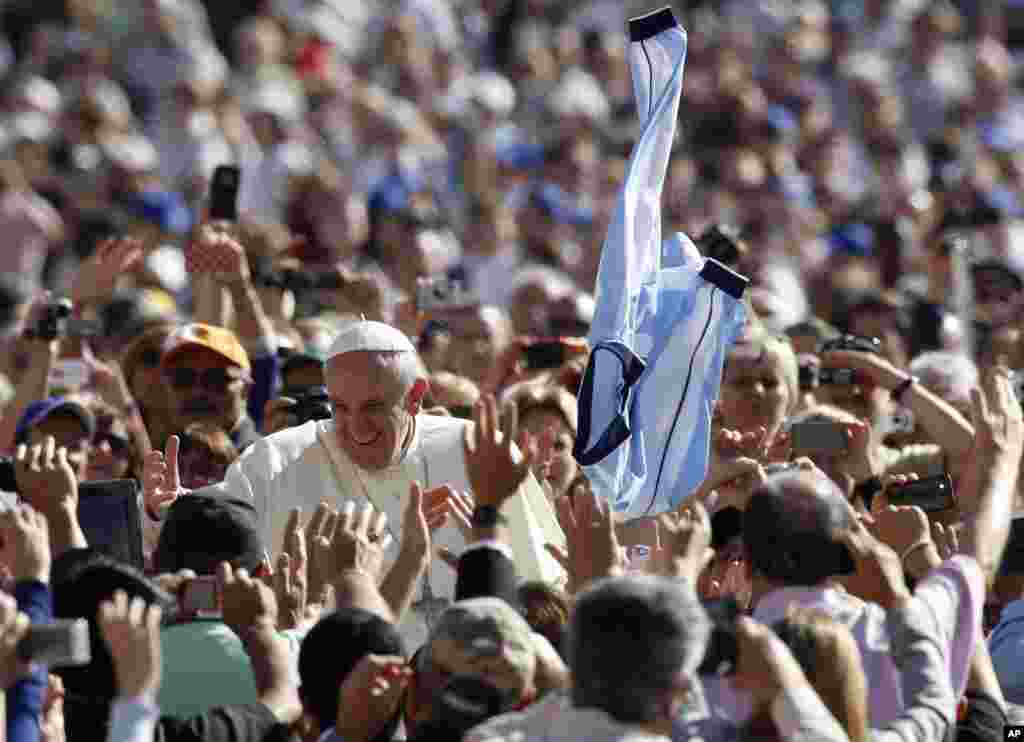 A faithful tosses in the air a jersey with the colors of the Argentine flag as Pope Francis greets faithful upon arrival for his weekly general audience in St. Peter&#39;s Square at the Vatican.