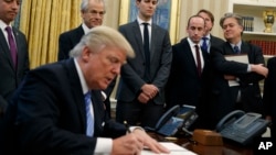 川普总统在白宫椭圆形办公室签署行政令。（2017年1月23日）