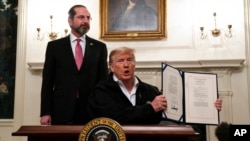 美国卫生与公共服务部长阿扎尔在旁边看着特朗普总统展示刚签署的对抗新冠病毒的开支法案（2020年3月6日）。