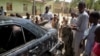 FILE - The wreckage of a car hit by an attack by Boko Haram fighters is seen surrounded by residents in the Adam Kolo district of Maiduguri, Nigeria, Feb. 24, 2021.