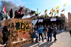 FILE - Pro-Iranian militiamen and their supporters set a fire in front of the U.S. embassy in Baghdad, Iraq, Jan. 1, 2020.