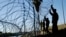 FILE - Members of the U.S. military install multiple tiers of concertina wire along the banks of the Rio Grande near the Juarez-Lincoln Bridge at the U.S.-Mexico border, Nov. 16, 2018, in Laredo, Texas. 