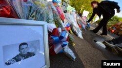 A picture of victim Drummer Lee Rigby, of the British Army's 2nd Battalion The Royal Regiment of Fusiliers is displayed with flowers left by mourners outside an army barracks near the scene of his killing in Woolwich, southeast London May 23, 2013.