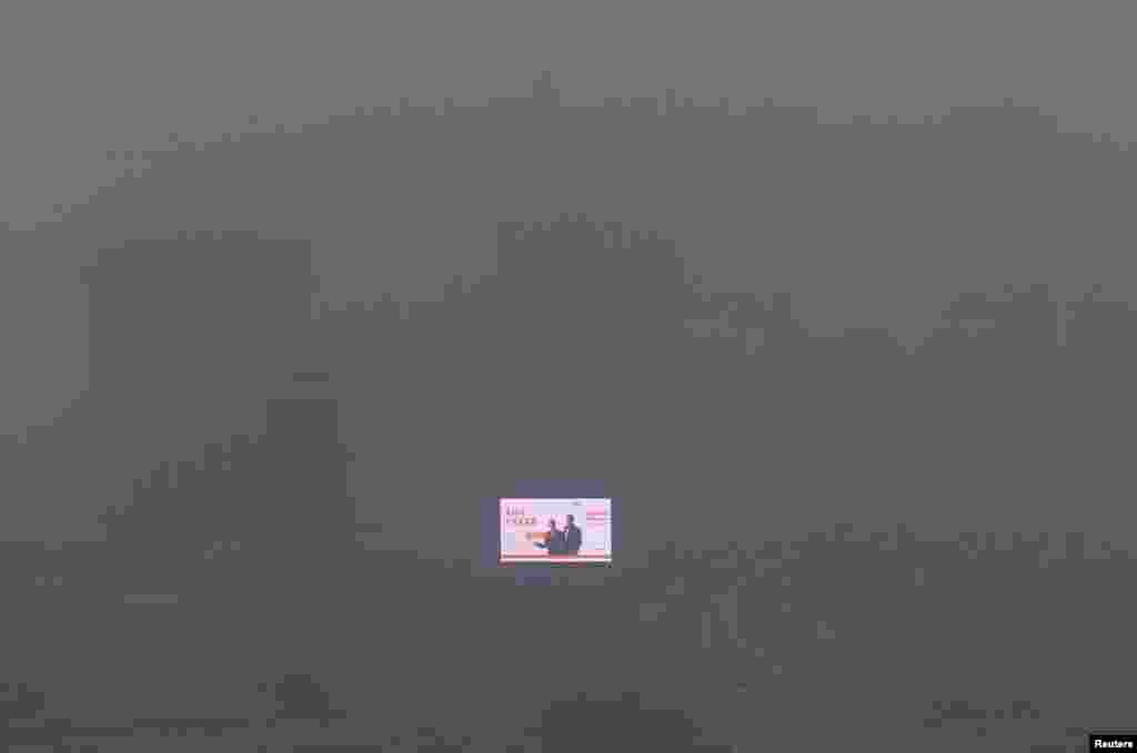 Sebuah layar elektronik terlihat pada bangunan di tengah asap tebal yang menyelimuti kota Shenyang, provinsi Liaoning, China.