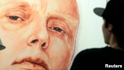 FILE - A man looks at a portrait of ex-spy Andrei Litvinenko by Russian artists Dmitry Vrubel and Viktoria Timofeyeva in the Marat Guelman gallery in Moscow.