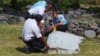 French gendarmes and police inspect a large piece of plane debris that was found on the beach in Saint-Andre, on Reunion Island in the Indian Ocean, July 29, 2015.