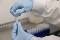 FILE - Scientists are seen working on a potential vaccine for COVID-19 at Cobra Biologics in Keele, Britain, April 30, 2020.