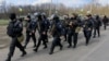 FILE - Members of the Ukrainian Interior Ministry walk past armored personnel carriers at a checkpoint near the town of Izium, eastern Ukraine, April 15, 2014.