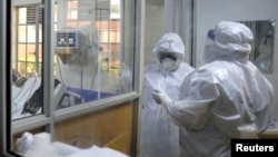FILE - Medical staff dressed in protective suits talk to each other as they treat coronavirus disease patients at the COVID-19 ICU of Machakos Level 5 Hospital, in Machakos, Kenya, Oct. 28, 2020. 