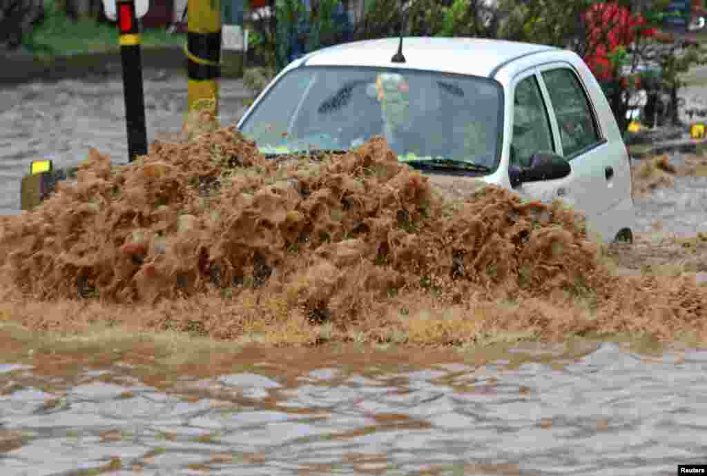 Sebuah mobil berusaha melewati jalanan yang terendam banjir di kota Guwahati, negara bagian Assam India.