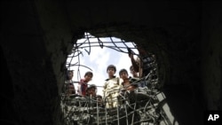 Quelques personnes regardent à travers un trou fait par un raid aérien un pont à Sanaa, au Yémen, 23 mars 2016.