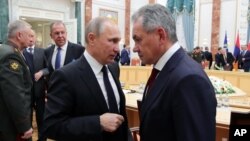 Russian President Vladimir Putin, foreground left, speaks to Russian Defense Minister Sergei Shoigu during the Collective Security Council of the Collective Security Treaty Organization (CSTO) summit in Minsk, Belarus, Nov. 30, 2017. 