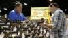 FILE - Julio Piloto, pemilik General Gun Shop (kiri), menunjukkan sebuah senpi Glock 19 kepada seorang pelanggan di pameran senjata yang diadakan oleh Florida Gun Shows, di Miami, Sabtu, 9 Januari 2016. (AP/Lynne Sladky)