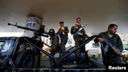 Police troopers stand on a police patrol vehicle stationed under a bridge in Sana'a, May 5, 2014, after they received flowers from activists showing their support for the military operation against al-Qaida militants in the south of the country. 