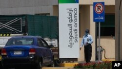 A security person wears a mask as he checks a vehicle entering a compound for Saudi Aramco in Jiddah, Saudi Arabia, Monday, March 9, 2020.