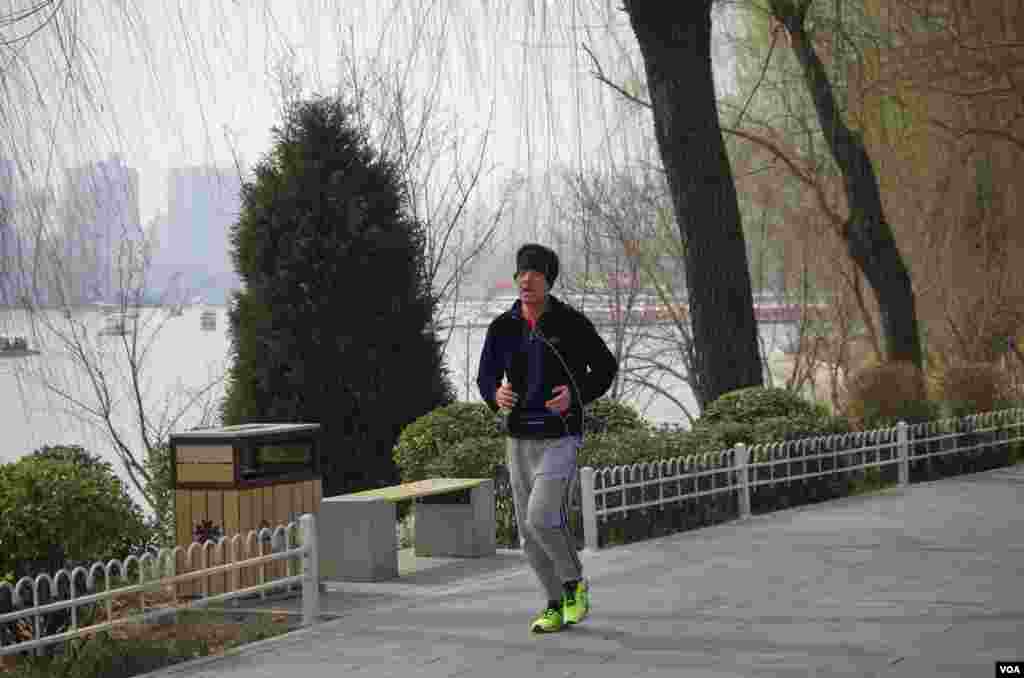 尽管雾霾严重，仍有市民不畏恶劣天气在湖边坚持锻炼 (曾谙 摄于2016年3月21日)