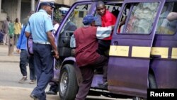 A September 2006 file photo shows a Kenyan policeman boarding a minibus after the vehicle was stopped for a traffic offence in the capital Nairobi.