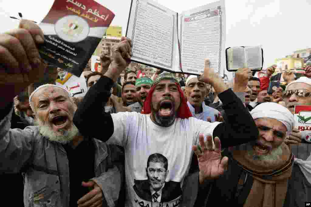 Supporters of Egyptian President Mohammed Morsi chant slogans as one holds up the Quran, Islam's holy book, during a demonstration after the Friday prayer, in Cairo, Egypt, Dec. 14, 2012.