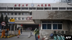 一名戴着口罩的男子走出北京大学人民医院的大门。（2020年2月21日）