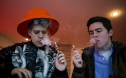 FILE - Customers puff on e-cigarettes at the Henley Vaporium in New York City, Dec. 18, 2013.