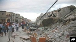 Haitians walk past damaged buildings in Port-au-Prince (file photo)