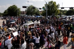 FILE - People gather as the horse-drawn carriage carrying the casket containing the body of George Floyd passes by on its way to Houston Memorial Gardens cemetery in Pearland, Texas, June 9, 2020.