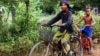 Im Chaem, a former Khmer Rouge cadre, is riding a bike along with her grandson in Anlong Veng, in Oddar Meanchey province in Cambodia, Sunday April 23, 2017. (Sun Narin/VOA Khmer)