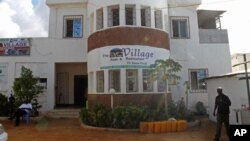 In this photo taken Tuesday, May, 22, 2012, Ahmed Jama, right, walks in front of his restaurant in Mogadishu Somalia. When Jama returned to Mogadishu after decades of war, he knew his years of business experience would help the war-ravaged city rebuild an