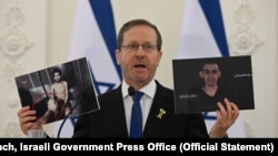 以色列总统艾萨克·赫尔佐格(Isaac Herzog)在维尔纽斯与立陶宛总统塔纳斯·瑙塞达(Gitanas Nausėda)共同出席会议时，手持巴勒斯坦恐怖组织拍摄的憔悴的以色列人质埃维亚塔·戴维(左)和罗姆·布拉斯拉夫斯基(右)的视频截图。(照片来源：以色列政府新闻办公室)