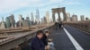 FILE - People eat their breakfast on the Brooklyn Bridge where the Manhattan skyline is seen in the background at the start of a work day, Dec. 3, 2018, in New York. 