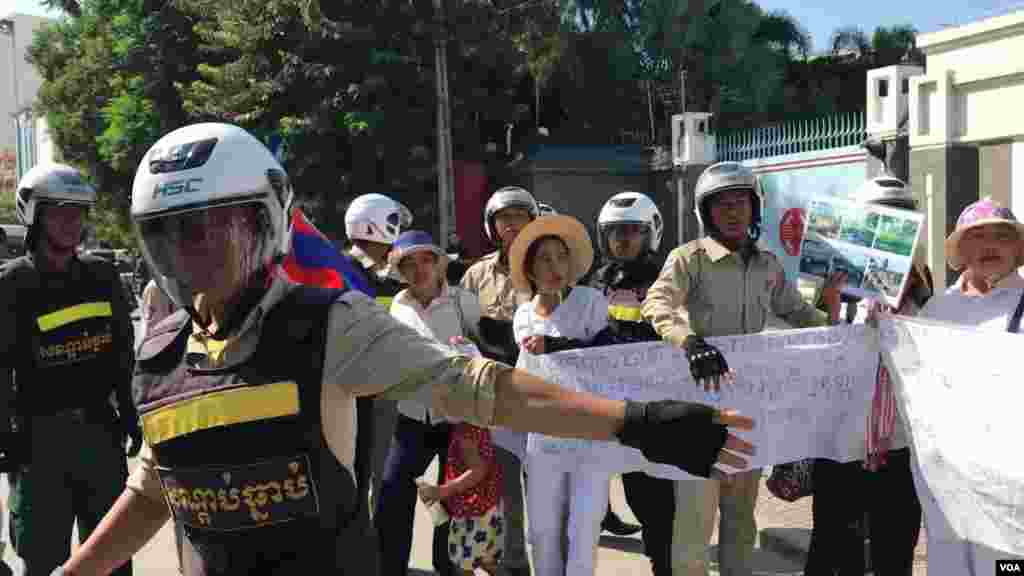 ក្រុម​សន្តិសុខ​កំពុង​ទាញ​ និង​អូស​ប្រជា​​ពលរដ្ឋ​​​មាន​ទំនាស់​ដី​ធ្លី​ជាមួយ​​ក្រុមហ៊ុន​ចិន ​Union Dev​el​o​pm​ent Group (UDG) ដែល​តវ៉ាសុំ​អន្តរាគមន៍​​នៅ​មុខ​ស្ថាន​ទូត​ចិន​ ​ ​​ចេញ​ពីស្ថានទូត​ នា​ថ្ងៃទី​១៣ ខែសីហា​ ឆ្នាំ​២០១៩។ (កាន់ វិច្ឆិកា/VOA) 