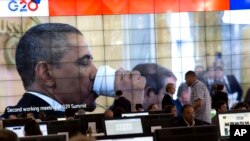 Presiden Obama minum dengan gelas kertas terlihat di layar lebar di media center KTT G-20 di St. Petersburg (6/9). Dalam KTT tersebut Obama mencari dukungan untuk menyetujui serangan terhadap Suriah atas penggunaan senjata kimia oleh rejim berkuasa di negara itu.