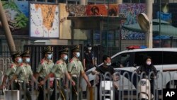 资料照片： 在美国驻北京大使馆外守卫的保安看一队武警走过。（2022年8月3日）