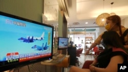 台北一家美发厅的顾客和理发师在观看电视报道的中国针对台湾的军演。（2022年8月4日）