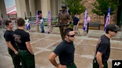 Anggota regu pemadam kebakaaran "Ironwood Hotshots" melewati patung pemadam kebakaran baru yang dipajang di luar Pusat Mobil Toyota di Prescott, Arizona (8/7). Wapres AS Joe Biden akan menghadiri upacara untuk mengenang 19 pemadam kebakaran yang tewas saat berupaya memadamkan kebakaran belukar dan hutan di negara bagian Arizona pekan lalu di kota ini.