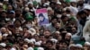 People hold the photo of police officer Mumtaz Qadri, the convicted killer of a former governor, during his funeral, in Rawalpindi, Pakistan, Tuesday, March 1, 2016. 