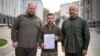 In a photo from Ukraine's Presidential Press Office, President Volodymyr Zelenskyy, center, with Prime Minister Denys Shmyhal, right, and head of the Supreme Council of Ukraine Ruslan Stefanchuk, holds an application for ''accelerated accession to NATO'' in Kyiv, Sept. 30, 2022. 