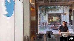 马斯克搬着一个洗手池盆进入在旧金山的推特总部。（2022年10月26日）