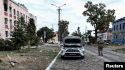 FILE - A Ukrainian serviceman patrols a street next to buildings damaged during fighting between Ukrainian and Russian forces in the Ukrainian-controlled town of Sudzha in Russia's Kursk region, Aug. 16, 2024. 