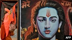অযোধ্যায় হিন্দু দেবতা রামের প্রতিকৃতির পাশ দিয়ে একজন ভক্ত হেঁটে যাচ্ছেন।