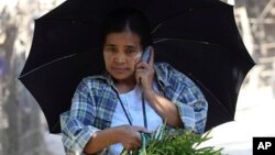 မြန်မာအိမ်ရှင်မတစ်ဦး လက်ကိုင်ဖုန်းဖြင့် စကားပြောနေစဉ်။