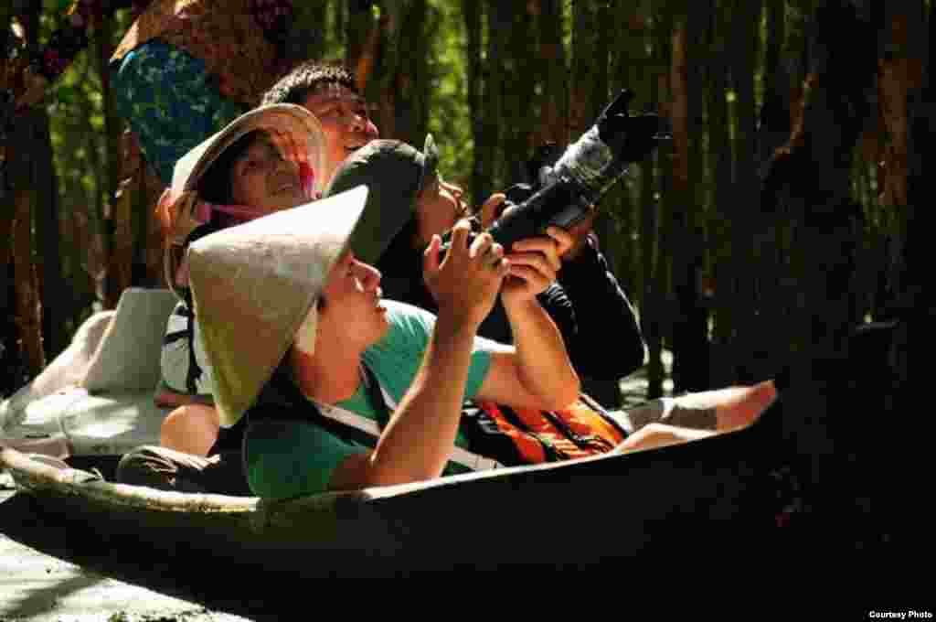 Seorang turis beraksi dengan kameranya saat mengunjungi hutan mangrove di Vietnam (Foto kiriman dari Võ Đình Anh Triết/pembaca VOA di Vietnam)