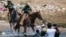 FILE - U.S. Customs and Border Protection mounted officers attempt to contain migrants as they cross the Rio Grande from Ciudad Acuña, Mexico, into Del Rio, Texas, Sept. 19, 2021. 