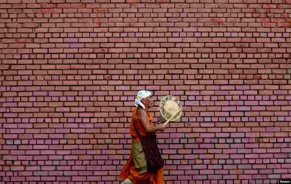 Seorang pendeta Budha bermain alat musik tradisional pada pagi hari di jalanan Kolombo, Sri Lanka.