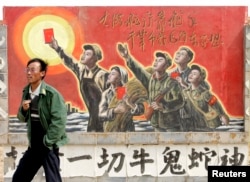 资料照：一名男子走过宁夏银川街头郊区的一处描写中国文革的宣传画。（2007年4月25日）