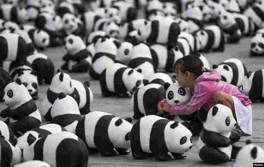 Seorang gadis memeluk patung beruang panda di Berlin, Jerman. (REUTERS/Thomas Peter)